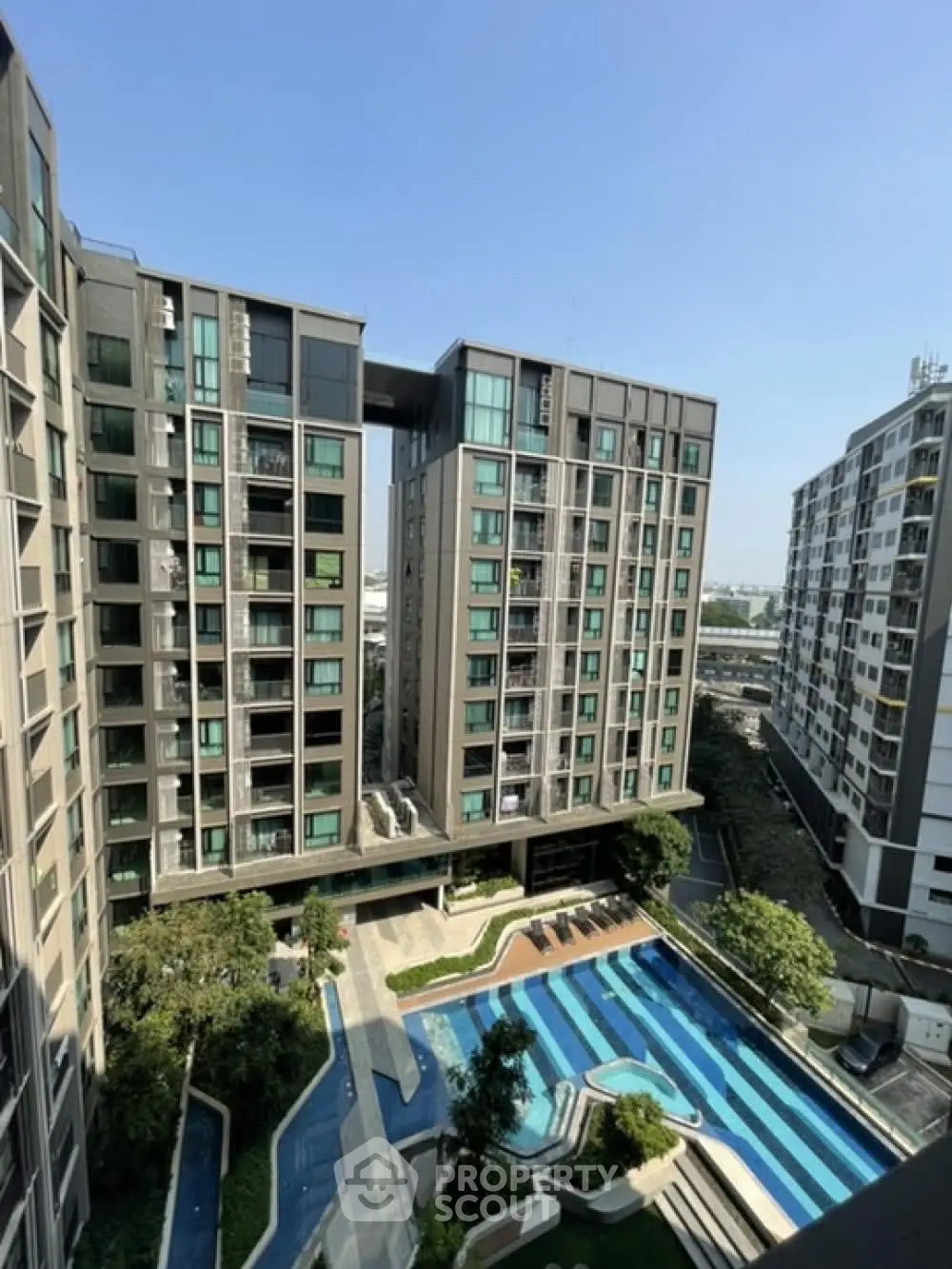 Modern apartment complex with pool and lush landscaping, offering urban living with resort-style amenities.