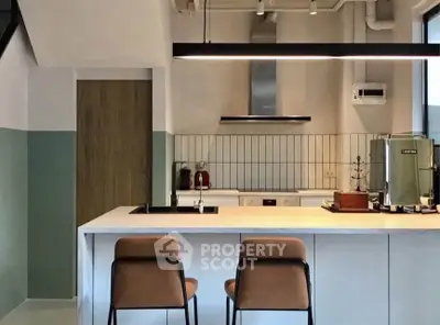 Modern kitchen with sleek design, featuring a central island and stylish bar stools, perfect for contemporary living.