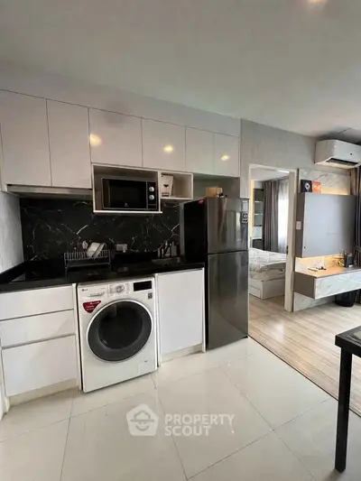 Modern kitchen with sleek appliances and open layout leading to a cozy bedroom.