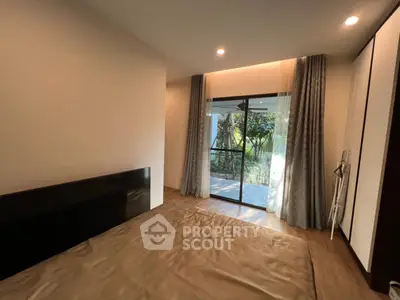 Spacious bedroom with large window and garden view, featuring modern decor and ample natural light.