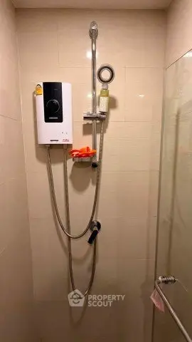 Modern bathroom shower area with water heater and glass partition.