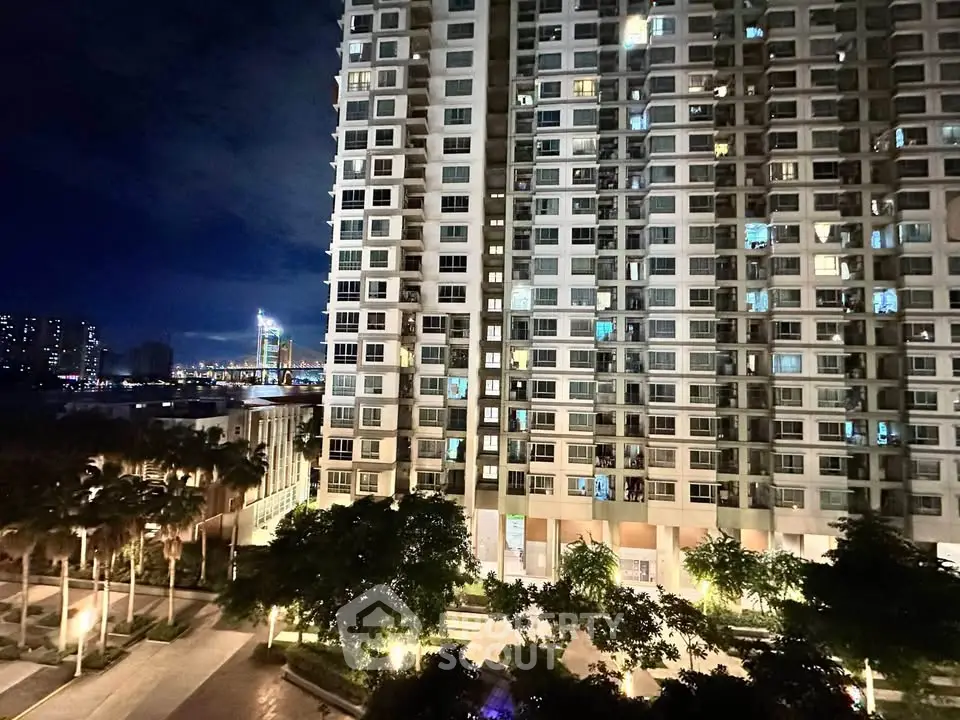Stunning night view of a modern high-rise building with city lights and lush greenery.