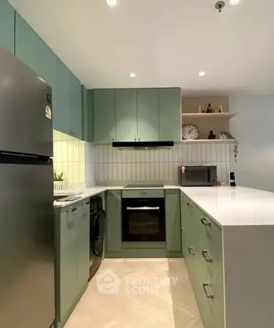 Modern kitchen with green cabinets, sleek appliances, and open layout design.