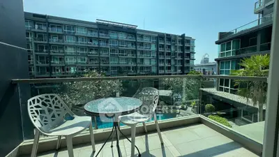 Modern balcony with stylish furniture overlooking a pool and contemporary building.