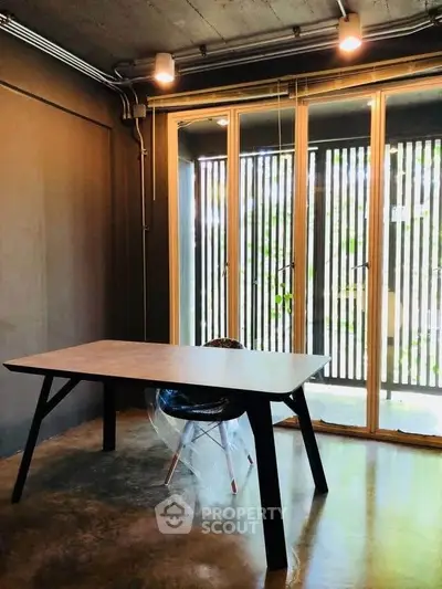 Modern study room with sleek table and chair, large windows, and industrial design.