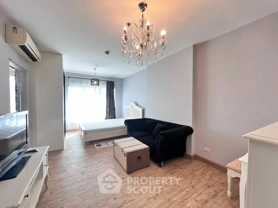 Elegant studio apartment with chandelier and modern furnishings