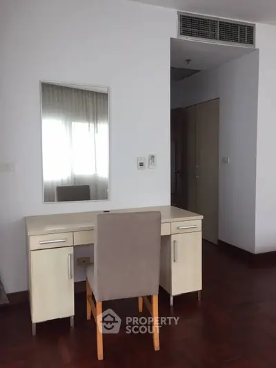 Spacious bedroom with elegant wooden flooring and stylish desk setup.