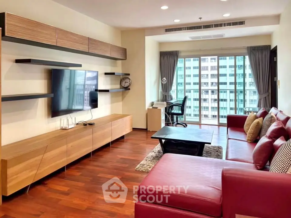 Spacious modern living room with red leather sofa and city view balcony.