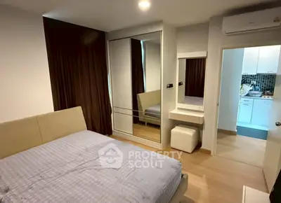 Modern bedroom with mirrored wardrobe and view into compact kitchen