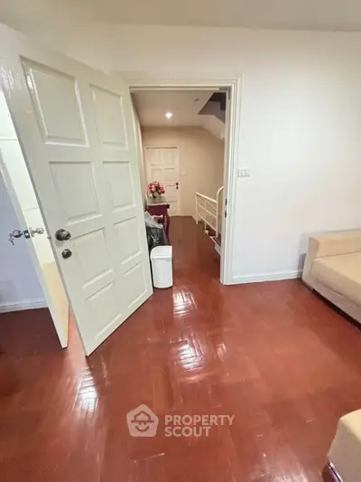 Spacious interior with wooden flooring and open door leading to a cozy living area.