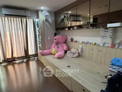 Spacious bedroom with wooden flooring and large teddy bear, perfect for a cozy family home.