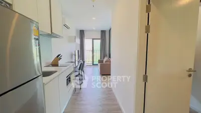 Modern apartment with open kitchen and cozy living room, featuring sleek appliances and natural light.