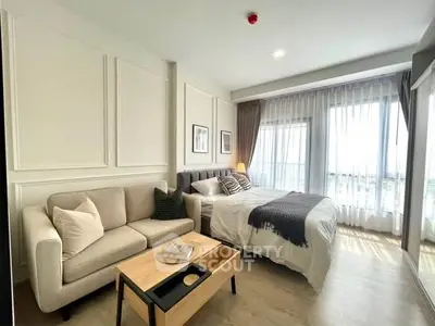 Modern bedroom with cozy seating area and large windows offering natural light.