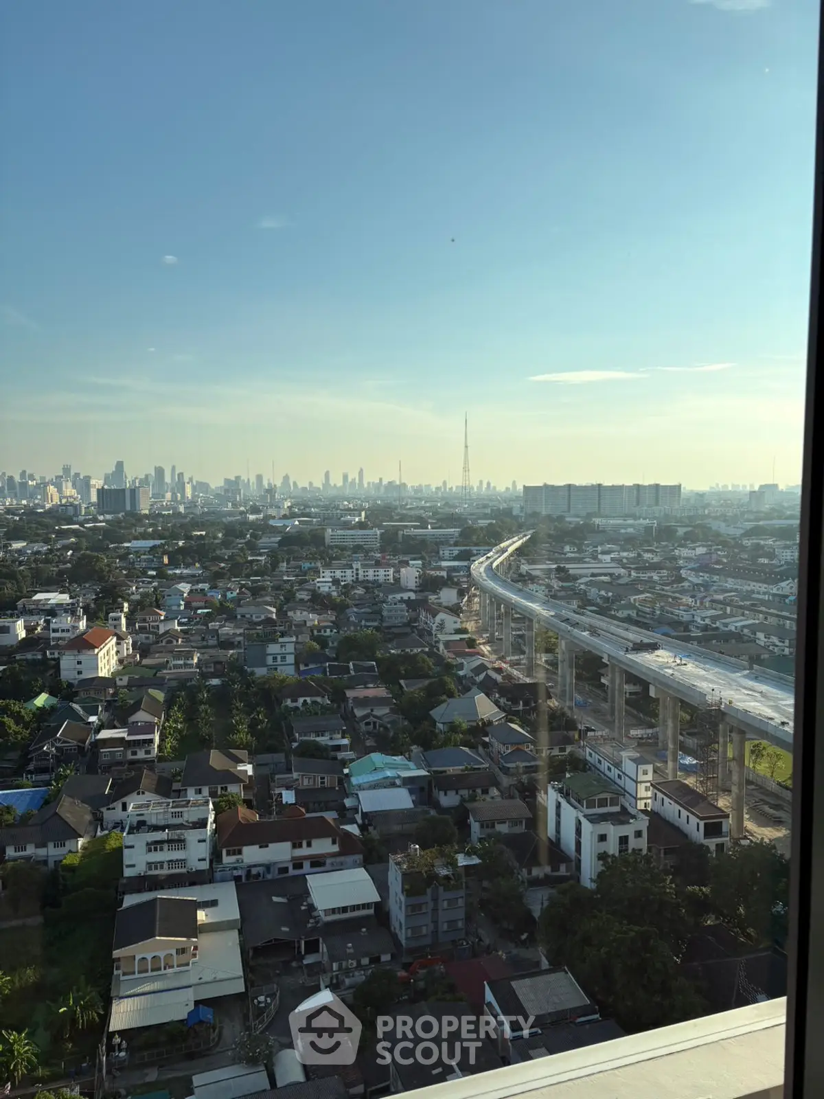 Stunning cityscape view from high-rise apartment window showcasing urban skyline and elevated train tracks.