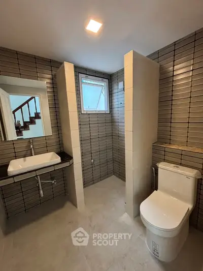 Modern bathroom with sleek tiles and contemporary fixtures, featuring a spacious shower area and elegant sink.