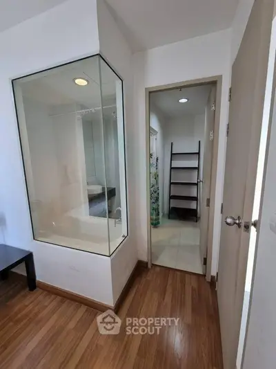 Modern apartment interior with glass-walled bathroom and wooden flooring