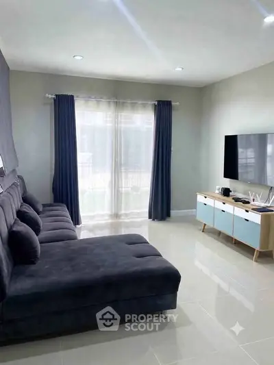 Modern living room with sleek furniture and large TV, perfect for relaxation and entertainment.
