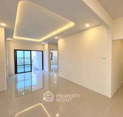 Spacious modern living room with sleek tile flooring and ambient ceiling lighting.