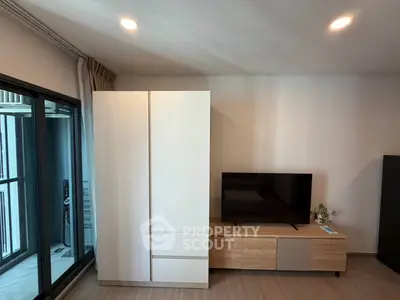 Modern living room with sleek TV stand and large wardrobe, featuring floor-to-ceiling windows for natural light.