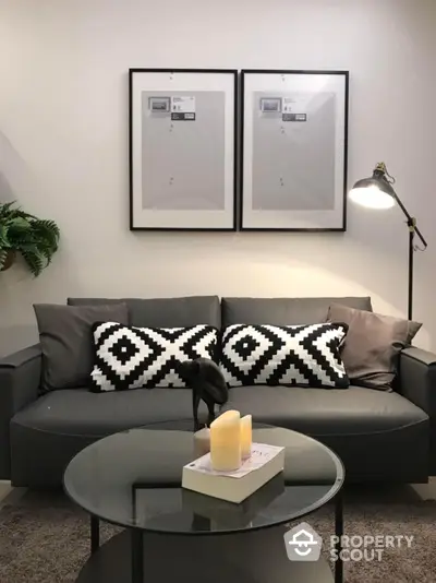 Chic modern living room with stylish grey sofa adorned with geometric patterned cushions, complemented by a sleek round coffee table and an elegant floor lamp, creating a cozy and inviting atmosphere.