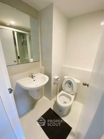 Modern compact bathroom with sleek fixtures and neutral tiles, featuring a mirror and a white toilet.