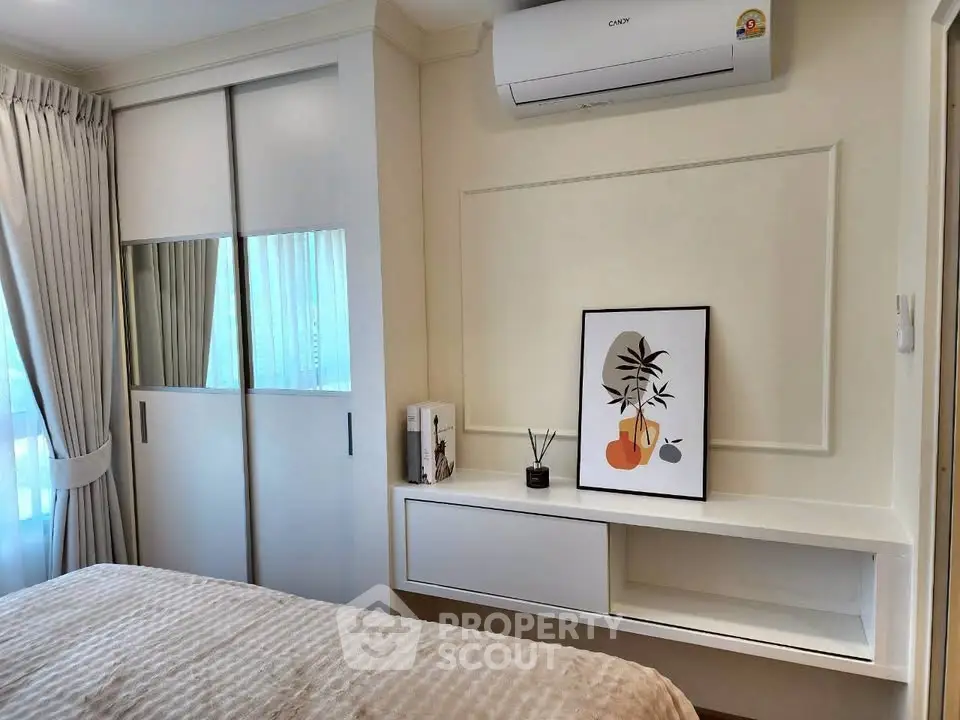 Chic bedroom with modern decor and air conditioning, featuring a stylish framed artwork and sleek storage solutions.