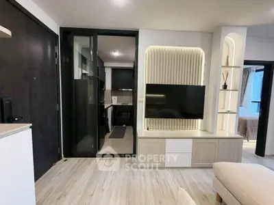 Modern living room with sleek TV unit and open kitchen layout in stylish apartment.