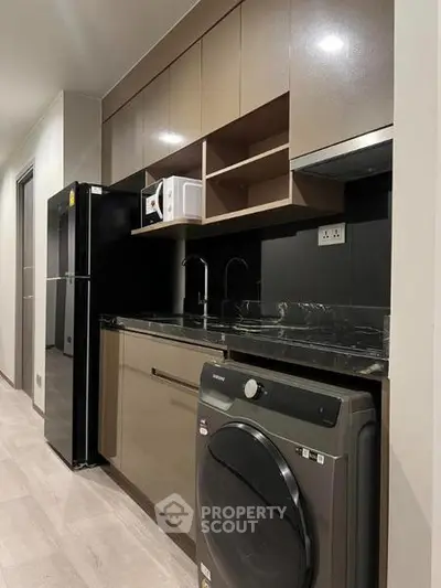 Modern kitchen with sleek cabinetry, black appliances, and integrated washing machine.