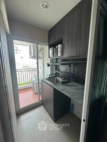 Compact kitchen with balcony view, featuring modern cabinetry and sleek countertops.