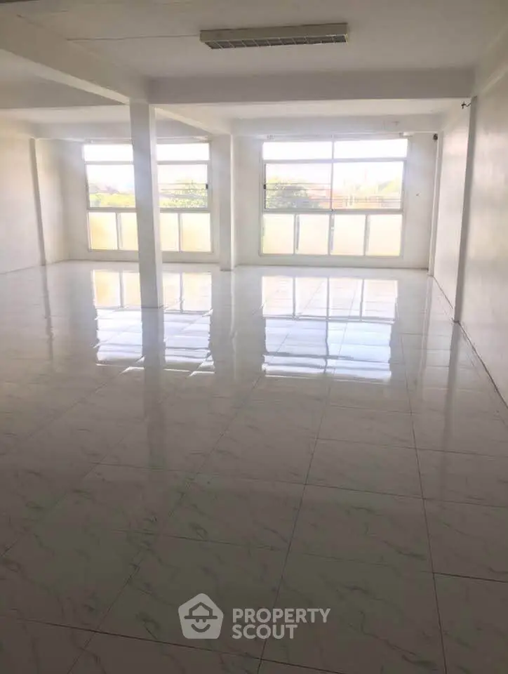 Spacious empty room with large windows and glossy tiled floor, ideal for customization.