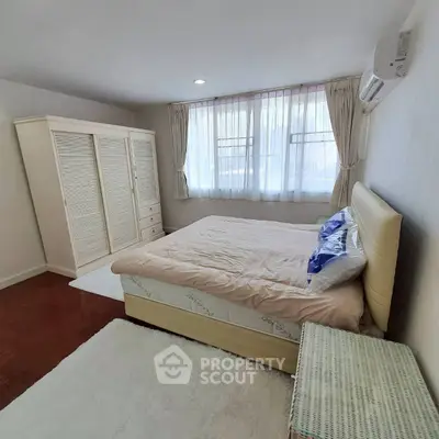 Cozy bedroom with natural light, featuring a plush bed and elegant wardrobe.