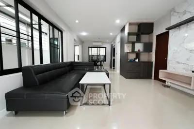 Spacious modern living room with sleek black sofa and elegant marble accents