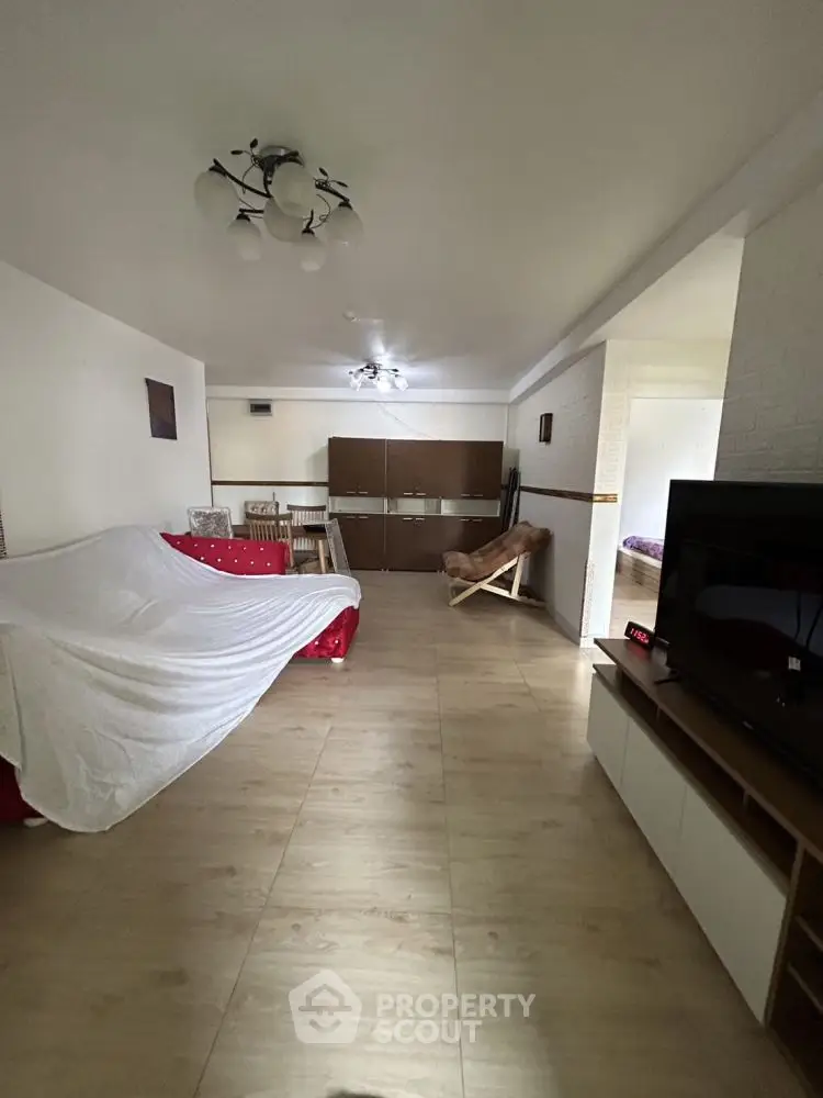 Spacious living room with modern decor and wooden flooring, featuring a cozy seating area and entertainment setup.