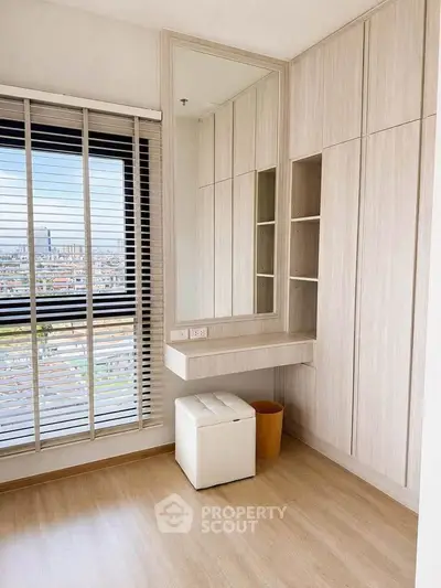 Bright modern bedroom with large window and built-in storage offering stunning city views.