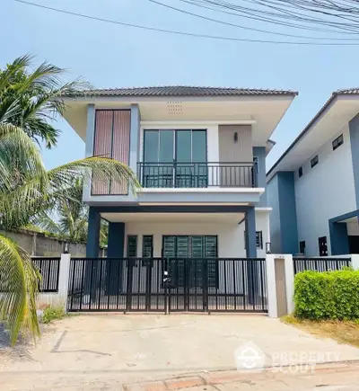 Modern two-story house with sleek design and gated entrance in a suburban neighborhood.