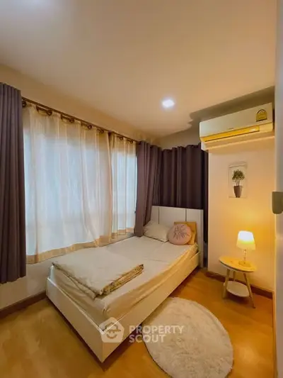 Cozy bedroom with natural light, wooden flooring, and modern air conditioning unit.