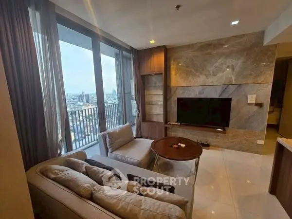 Modern living room with city view, elegant furnishings, and large windows.