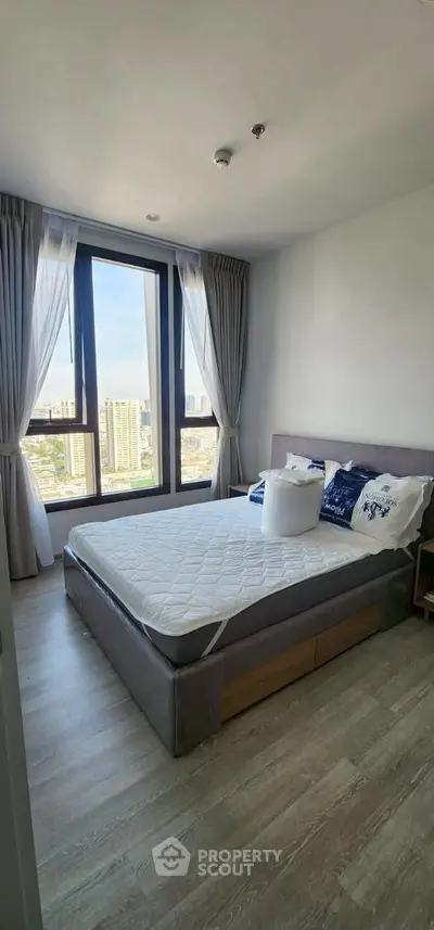 Bright bedroom with large window and city view, featuring modern decor and cozy ambiance.
