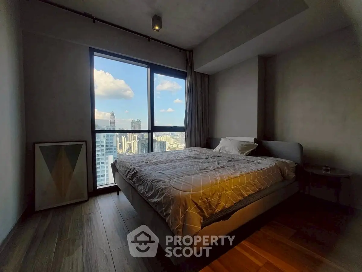 Modern bedroom with city view and stylish decor in high-rise apartment.