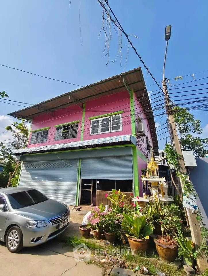 Charming pink two-story house with garage and lush garden in a serene neighborhood.