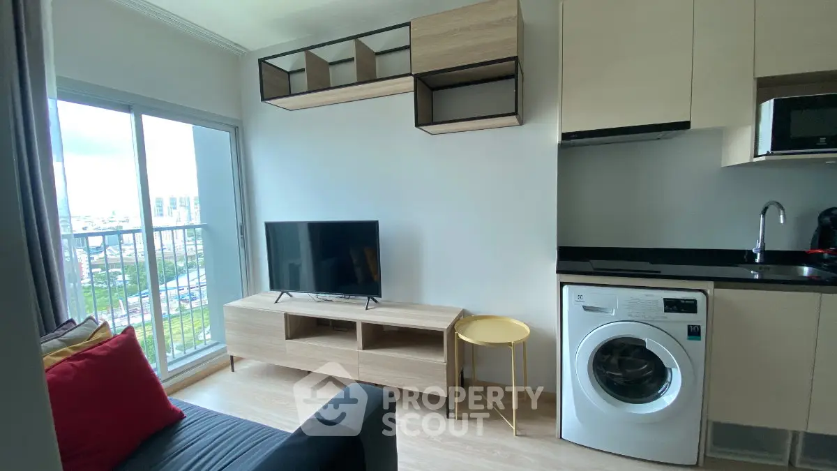 Modern living room with balcony view, sleek furniture, and integrated kitchen appliances.