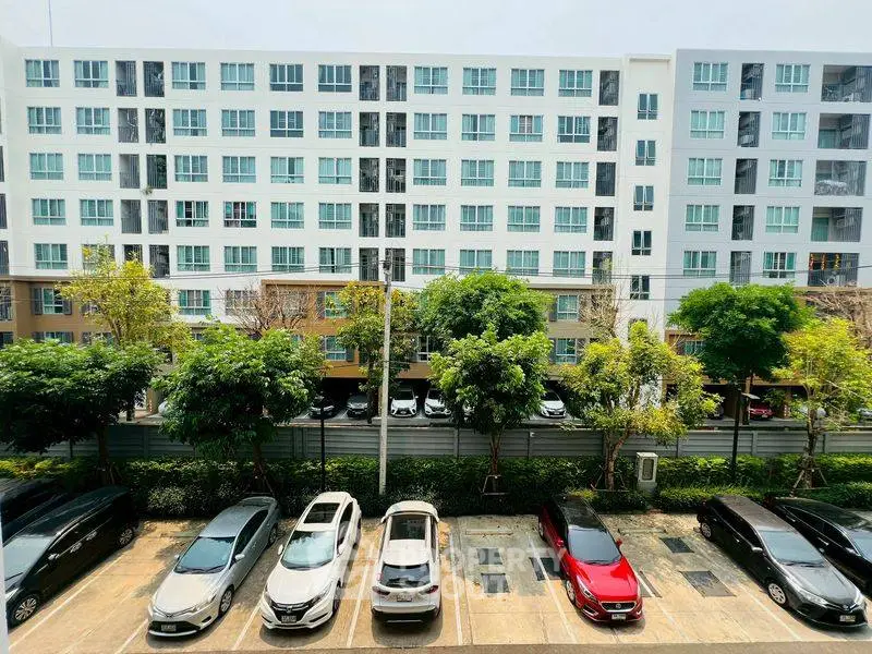 Modern apartment building with parking lot and lush greenery, ideal urban living.