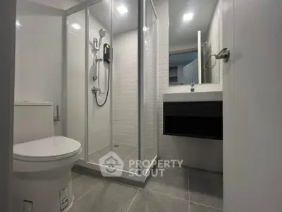 Modern bathroom with glass shower enclosure and sleek fixtures in contemporary apartment.