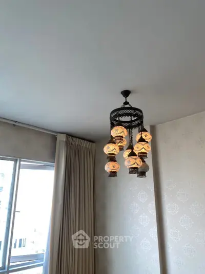 Elegant interior with ornate chandelier and patterned wallpaper, showcasing luxury living space.