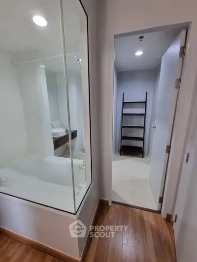 Modern bathroom with glass-enclosed bathtub and sleek shelving unit
