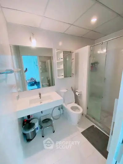 Modern bathroom with glass shower, sleek fixtures, and bright lighting.