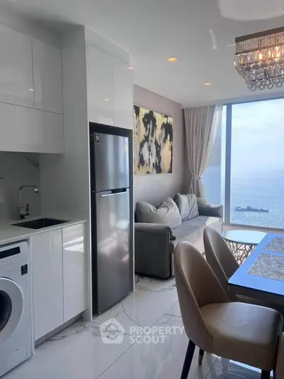 Luxurious open-plan living room with ocean view, modern kitchen, and elegant decor.