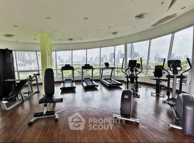 Spacious gym with modern equipment and city skyline view, perfect for fitness enthusiasts.