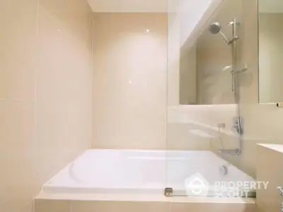 Modern bathroom with a pristine white bathtub and sleek fixtures, complemented by neutral beige wall tiles for a serene ambiance.