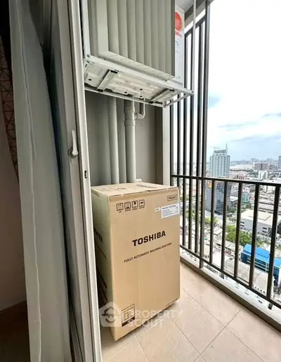 High-rise balcony with city view and boxed Toshiba washing machine.